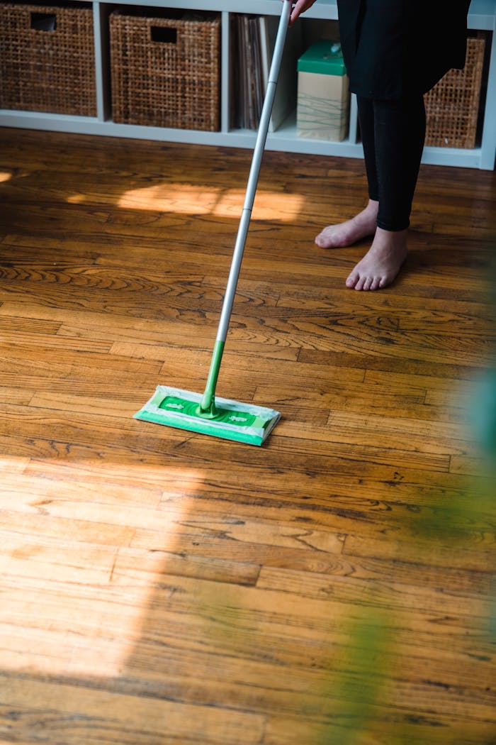 services-02 Modern cleaning service image featuring a person with a green mop on a wooden floor indoors.