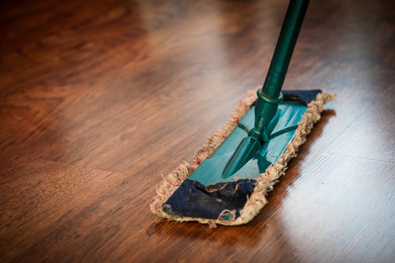 hero-img-02 A detailed view of a mop cleaning a wooden floor, showing texture and pattern.